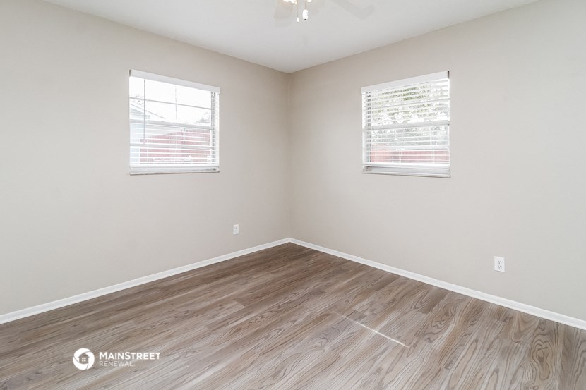 the spacious living room with wood flooring and two windows