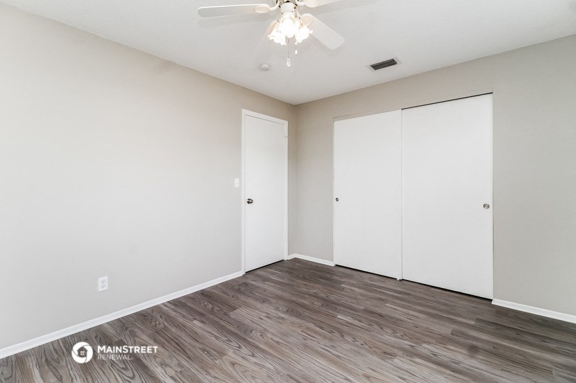the spacious living room with white walls and wood flooring