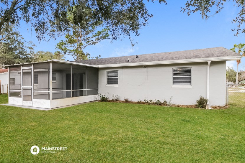 a small white house with a lawn and a tree