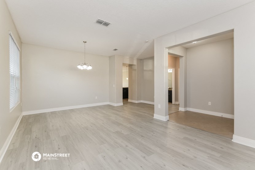 a renovated living room and dining room with wood floors and white walls