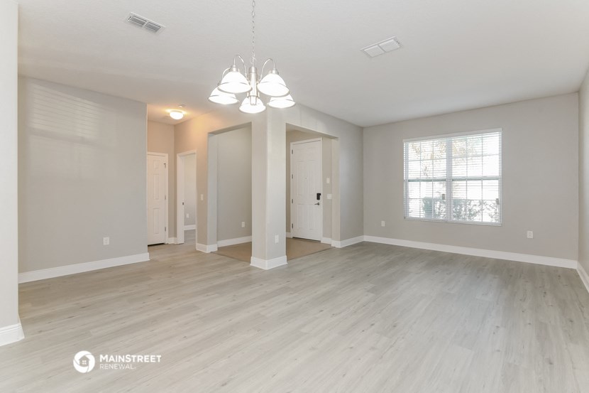 the spacious living room with hardwood floors and white walls
