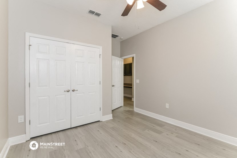 the living room of a home with white doors and a ceiling fan