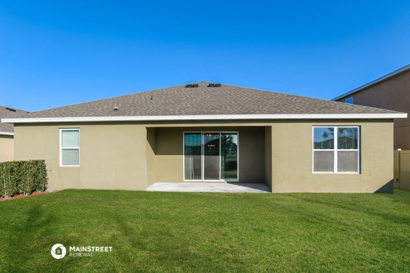 a beige house with a green lawn and a blue sky