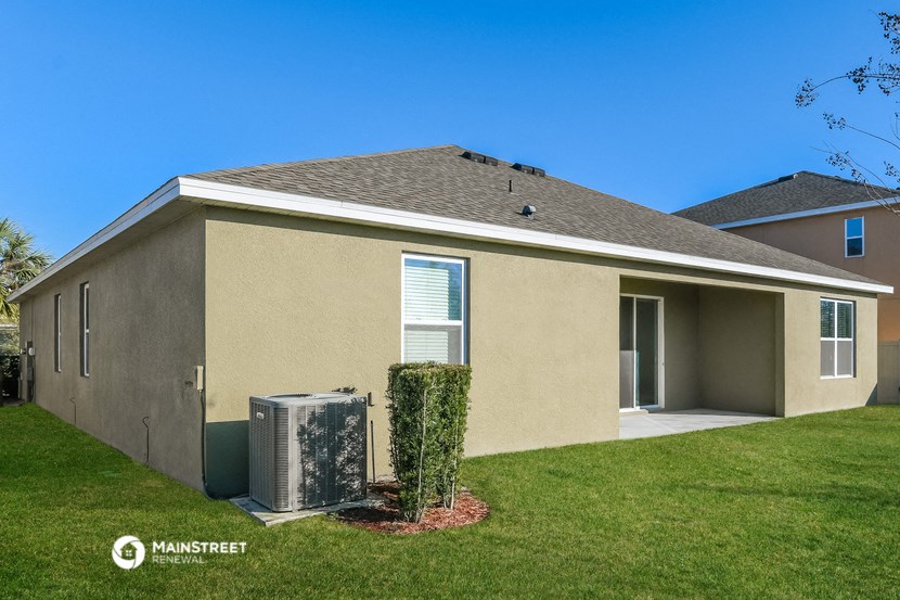 a beige house with a heater in the grass