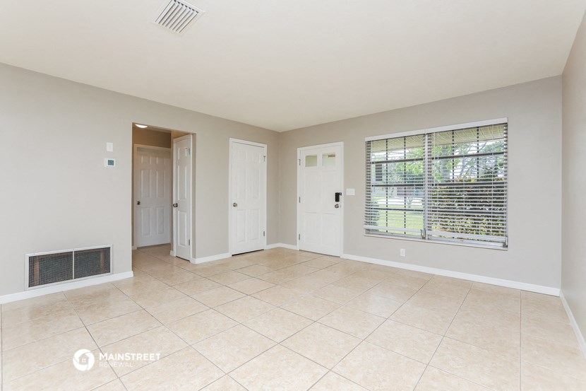 an empty living room with a large window and tiled floors