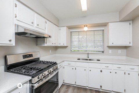 a kitchen with white cabinets and stainless steel appliances and a sink
