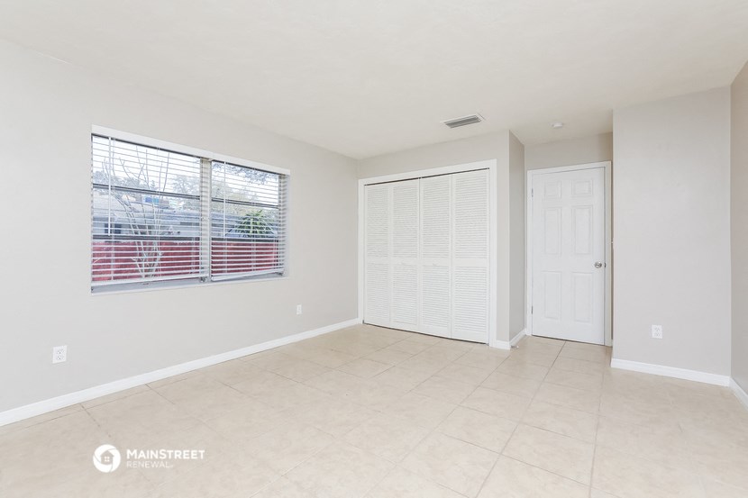a spacious living room with a large window and a tiled floor