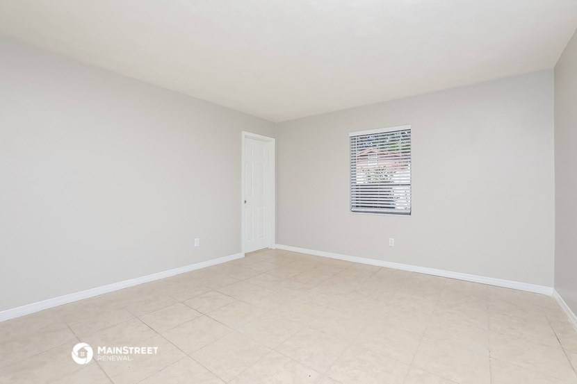 a spacious living room with white walls and a tiled floor
