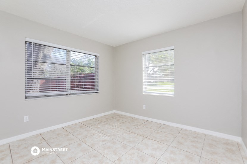 an empty room with two windows and a tiled floor