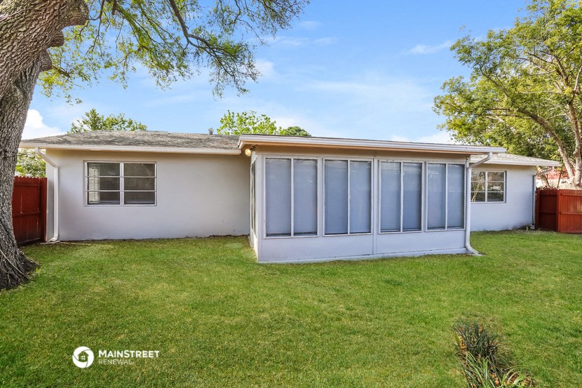 a small white house with a lawn and a tree