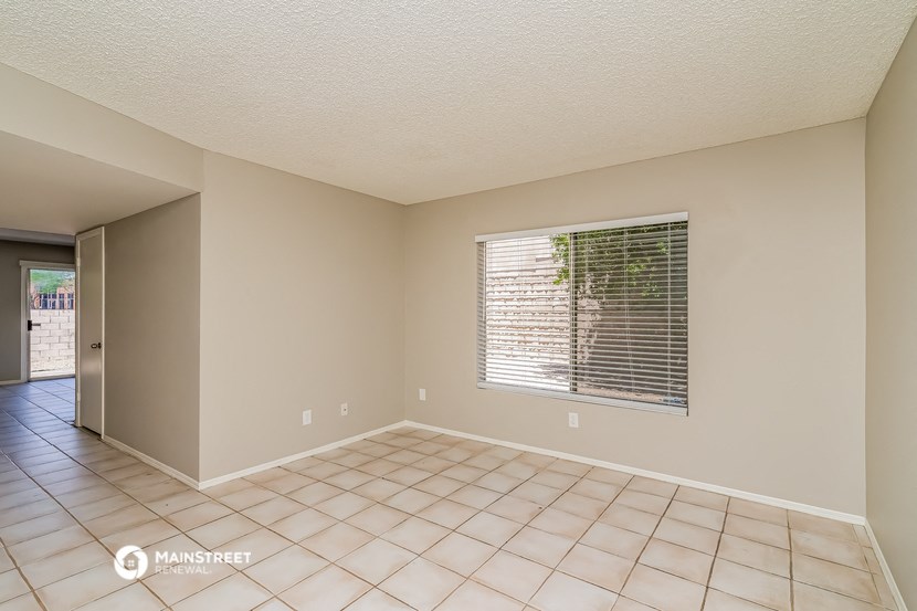 an empty living room with a large window and a tiled floor