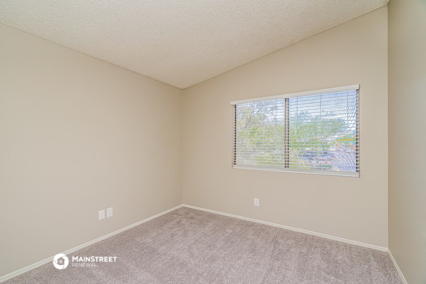 an empty room with a window and a carpeted floor