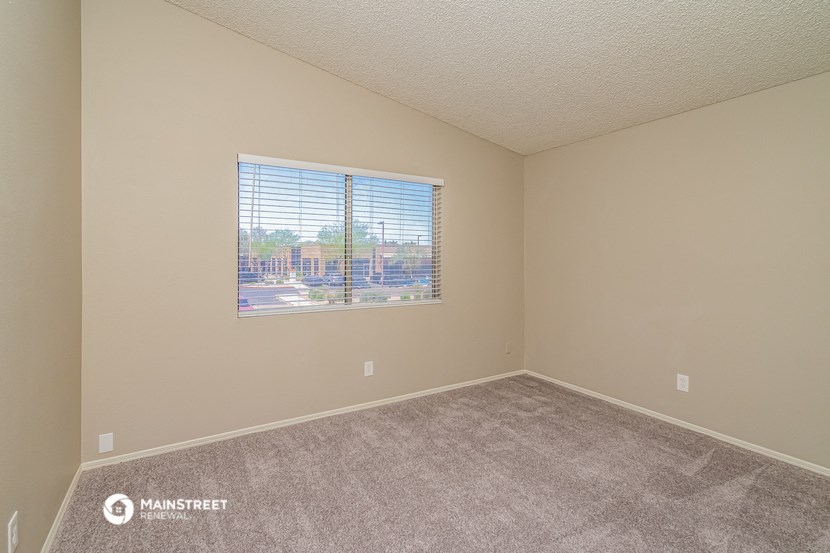 an empty living room with a window and carpet