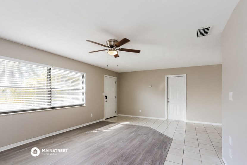 an empty living room with a ceiling fan and a large window