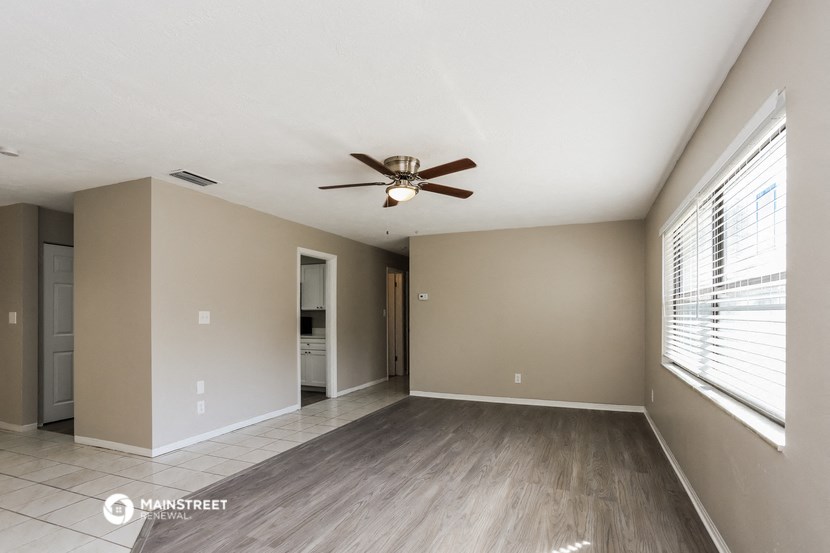 an empty living room with a ceiling fan and a large window