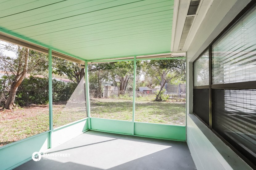 a screened in porch with glass doors overlooking a yard