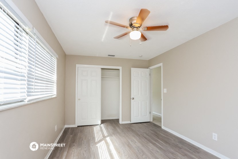 an empty room with a ceiling fan and a window