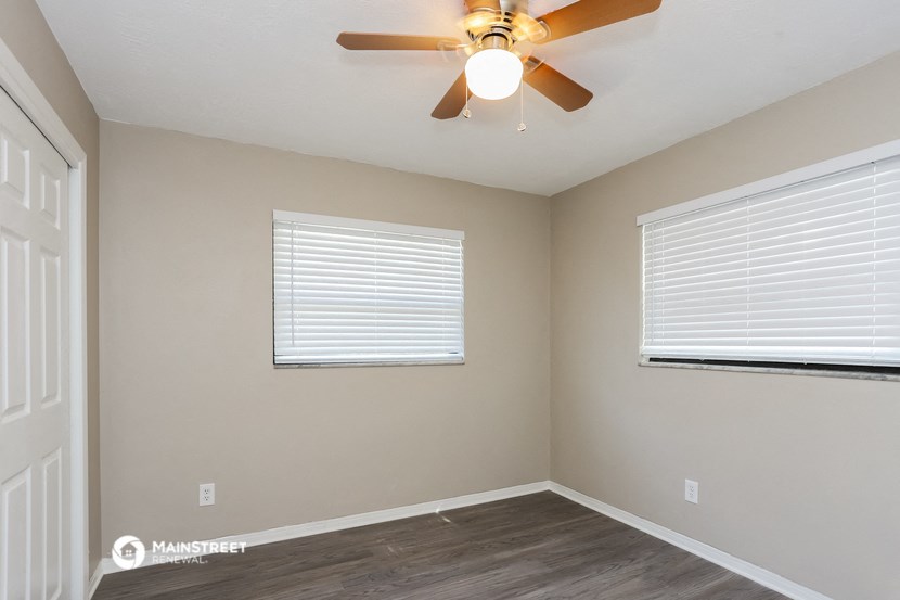 the interior of a bedroom with a ceiling fan and two windows
