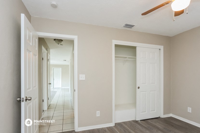 a bedroom with two closets and a hallway with a ceiling fan