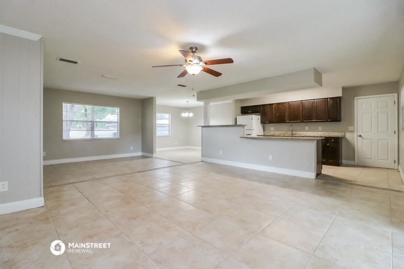 an empty living room and kitchen with a ceiling fan