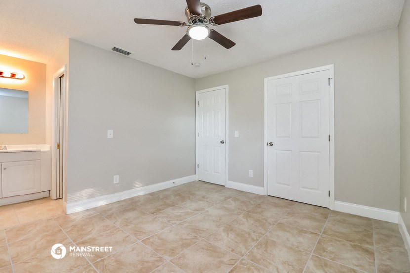 the spacious living room with ceiling fan and tile flooring