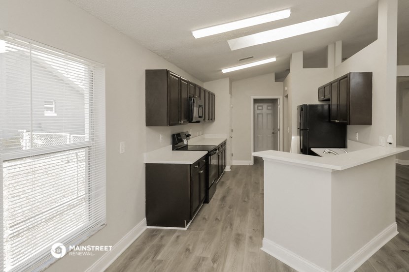 an empty kitchen with a large window and a counter with black cabinets