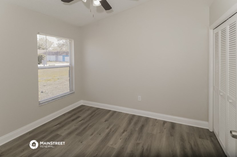 the living room of an apartment with wood flooring and a window