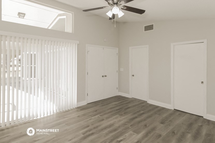 an empty living room with white walls and a ceiling fan