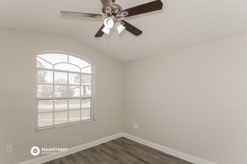 the living room has a ceiling fan and a large window