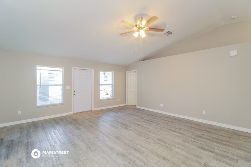 the living room of an empty house with a ceiling fan