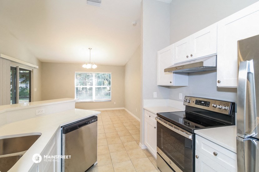 an empty kitchen with white cabinets and stainless steel appliances