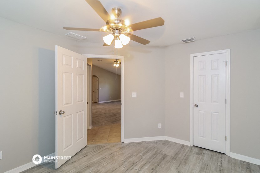a bedroom with a ceiling fan and a door to a hallway