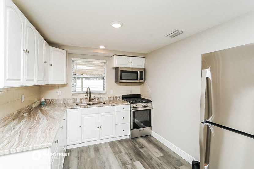a renovated kitchen with white cabinets and stainless steel appliances