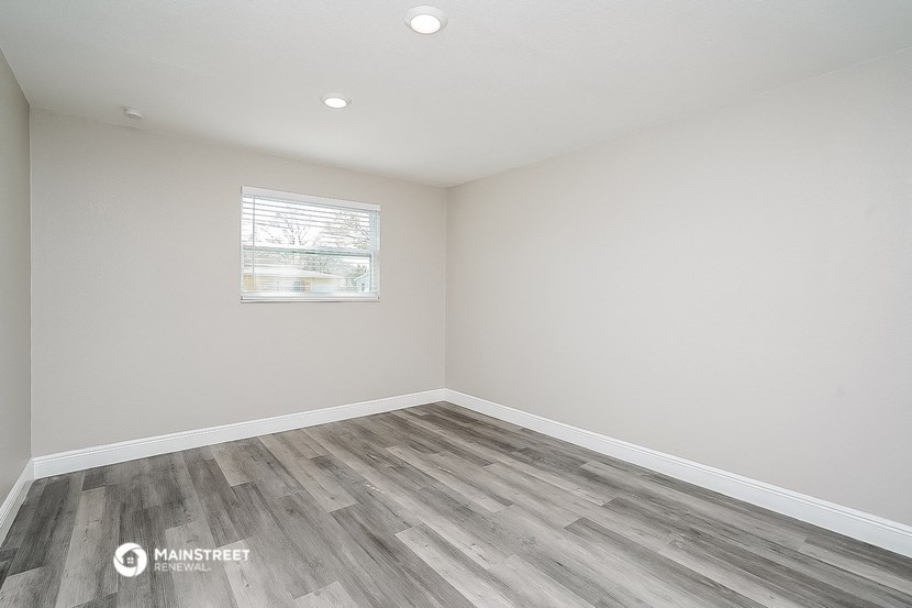 the living room of a home with wood flooring and a window