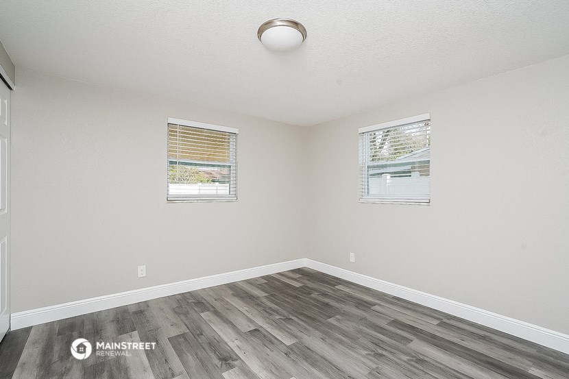 the spacious living room with wood flooring and two windows