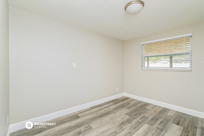 the spacious living room with wood flooring and a window