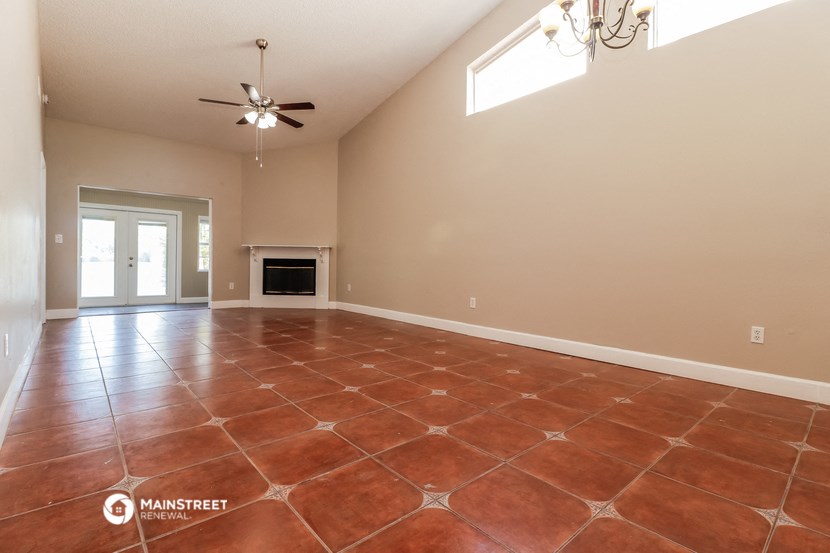 an empty living room with a fireplace and a ceiling fan
