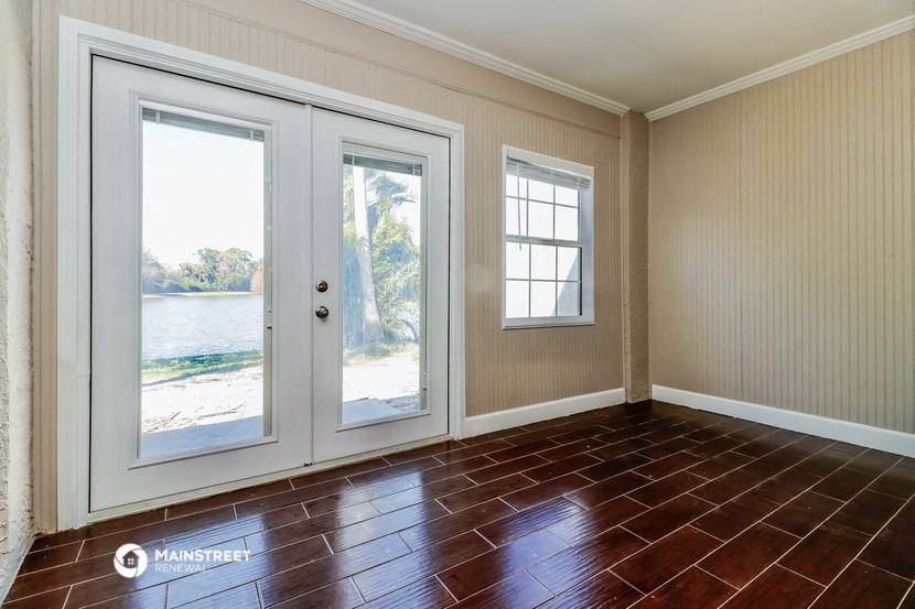 a living room with two doors and a window overlooking the water