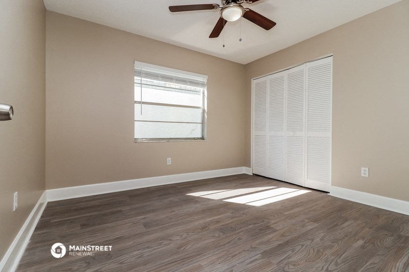 an empty living room with a ceiling fan and a window