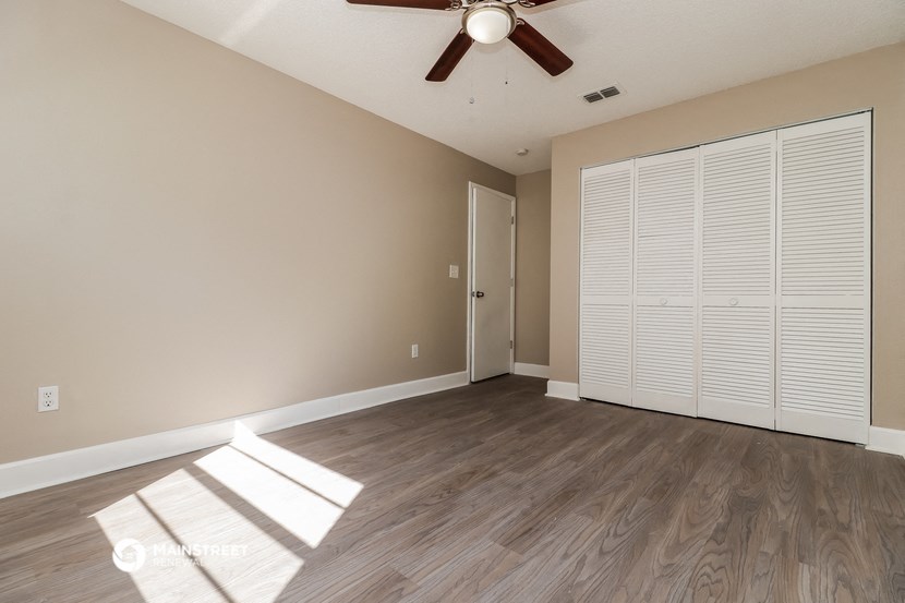 an empty living room with a ceiling fan and a closet