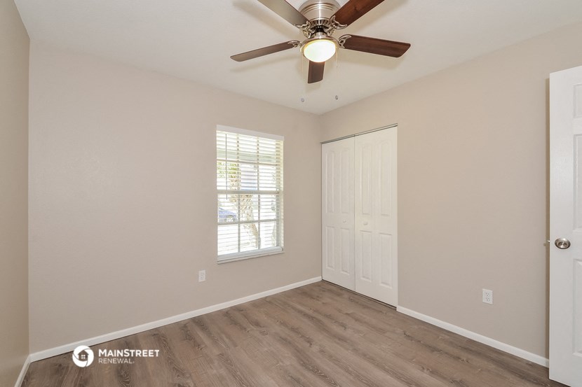 the spacious living room with a ceiling fan