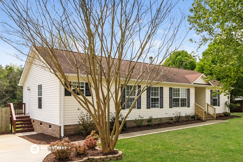 a white house with a yard and a tree in front of it