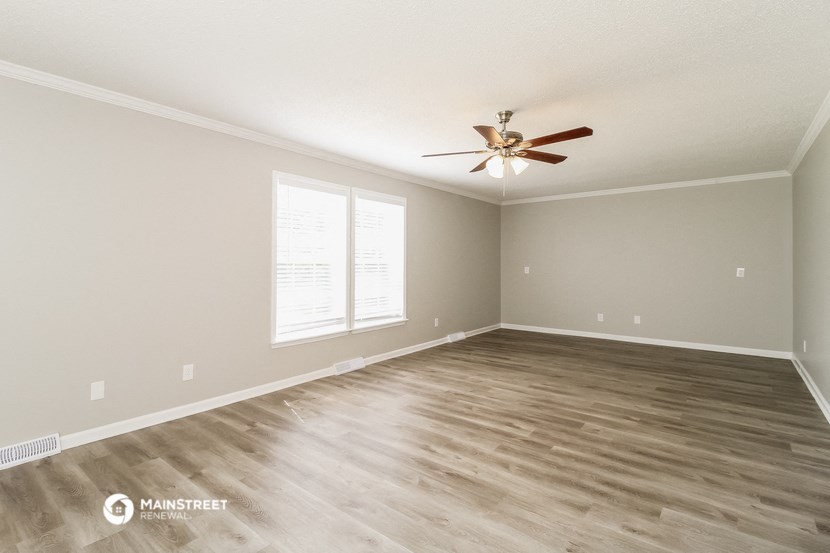 the spacious living room with hardwood floors and a ceiling fan