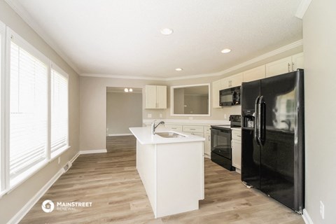 a white kitchen with a black refrigerator and a sink