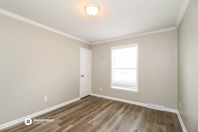 the spacious living room with hardwood flooring and a window