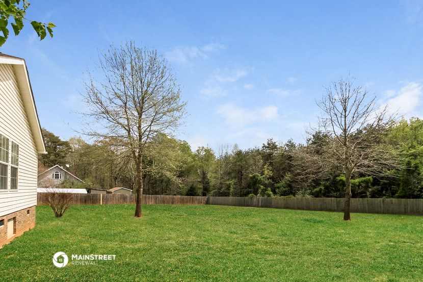 a backyard with a fence and two trees