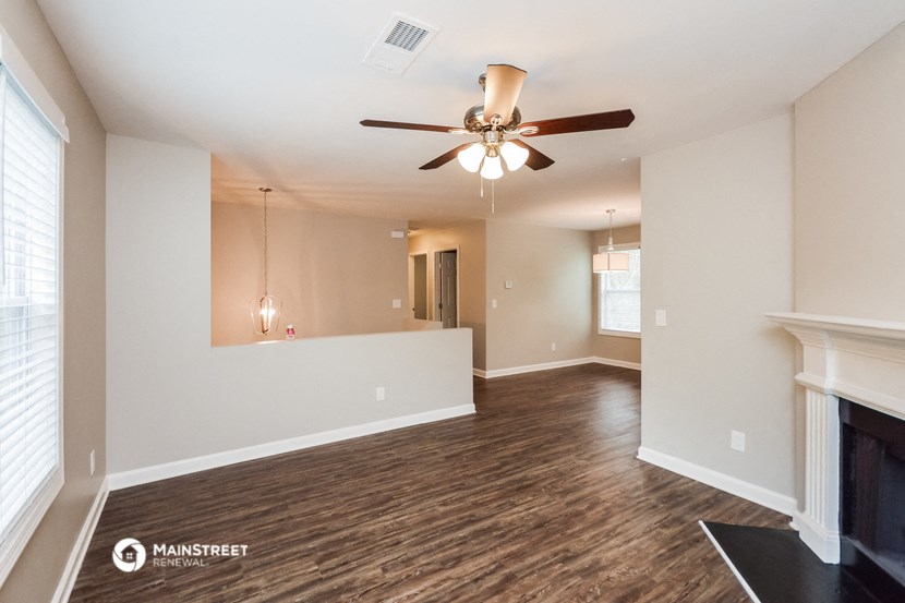 an empty living room with a ceiling fan and a fireplace