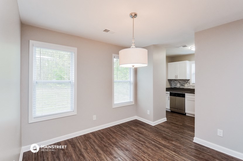 the living room and kitchen of an apartment with wood flooring and a large window