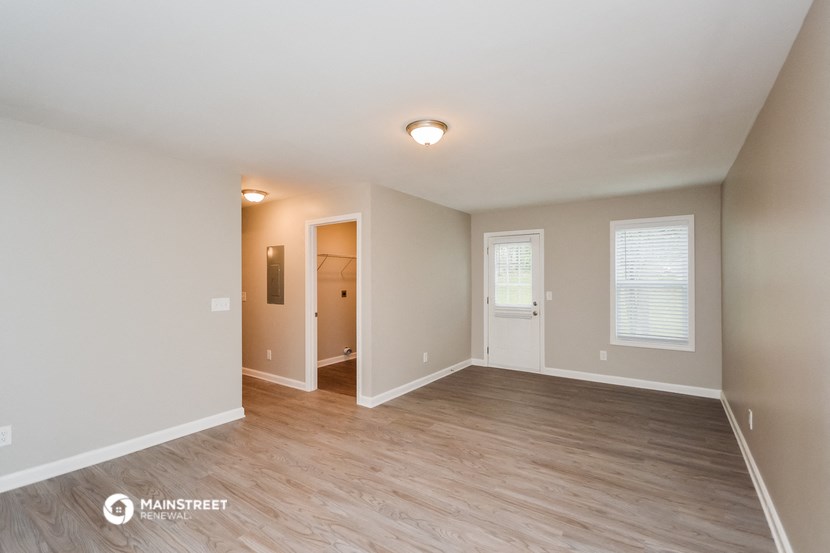 the spacious living room with wood flooring and white walls