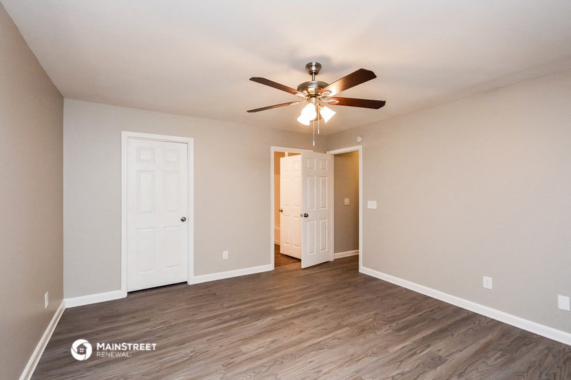 the spacious living room with ceiling fan and wood flooring